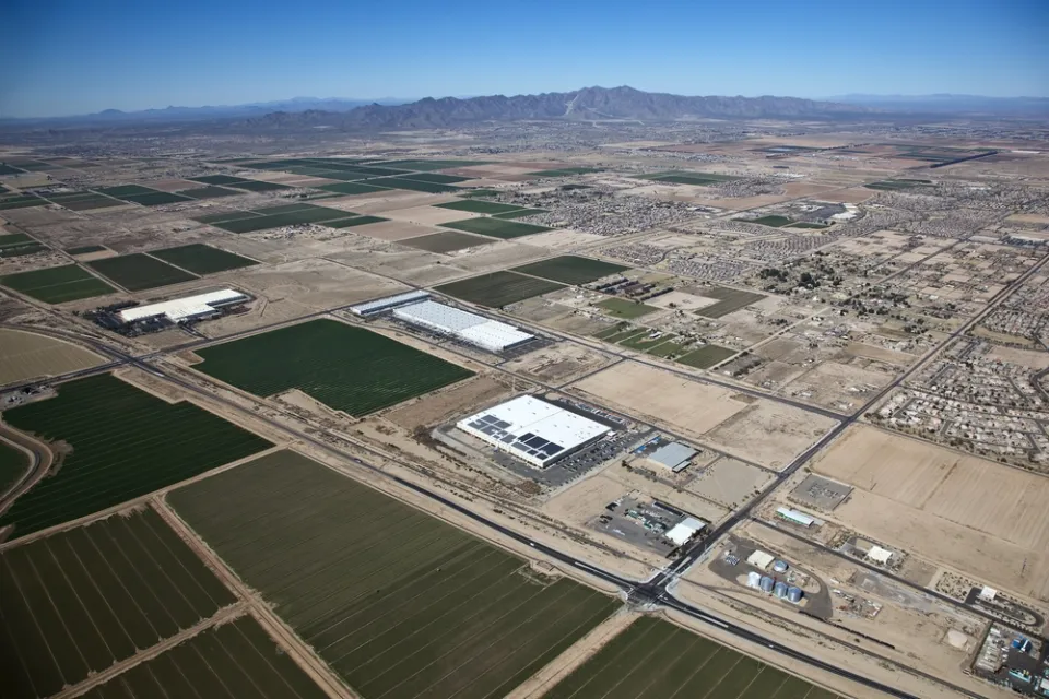 Sprawling warehouses and agricultural landscapes mix with low-rise residential developments in the Arizona desert.